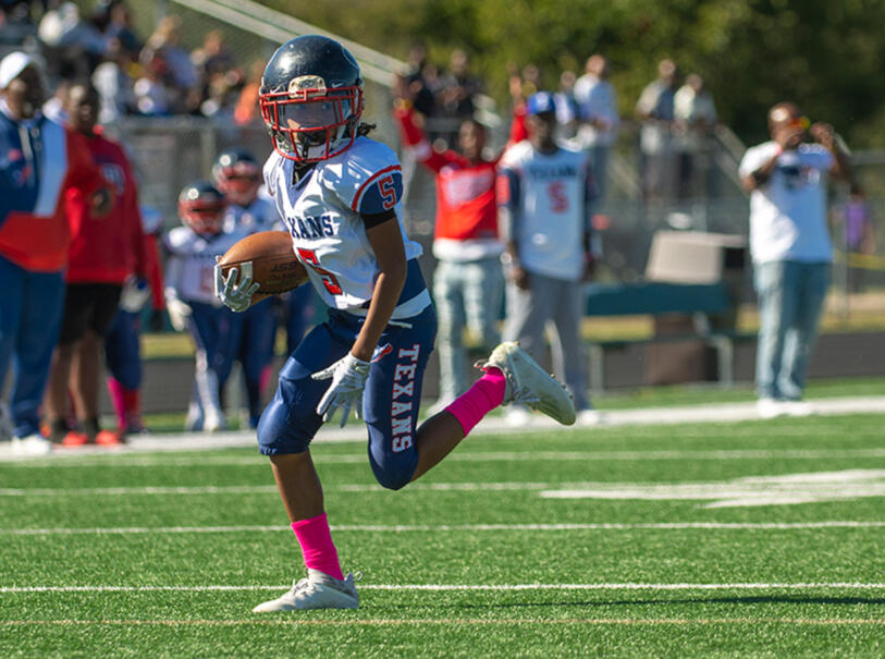 Peewee football player in stride towards a touchdown.